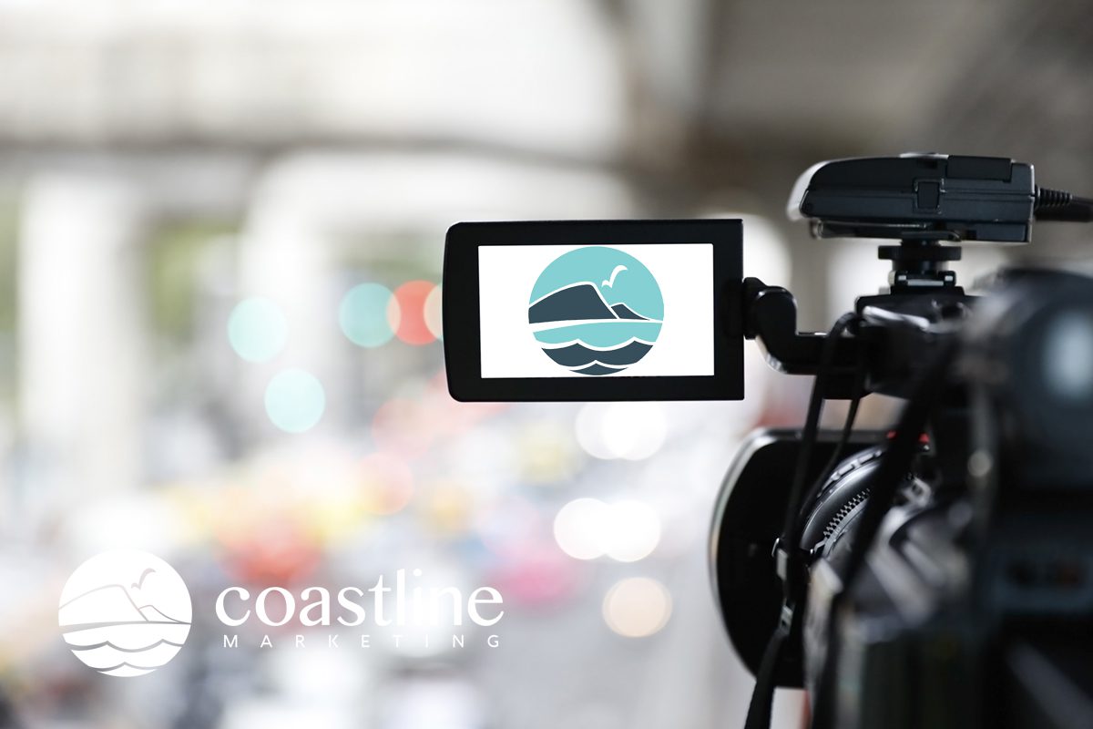 Real Estate Videos by Coastline Photography Videography and Marketing. A picture of a camera has Coastline's Logo in the viewfinder